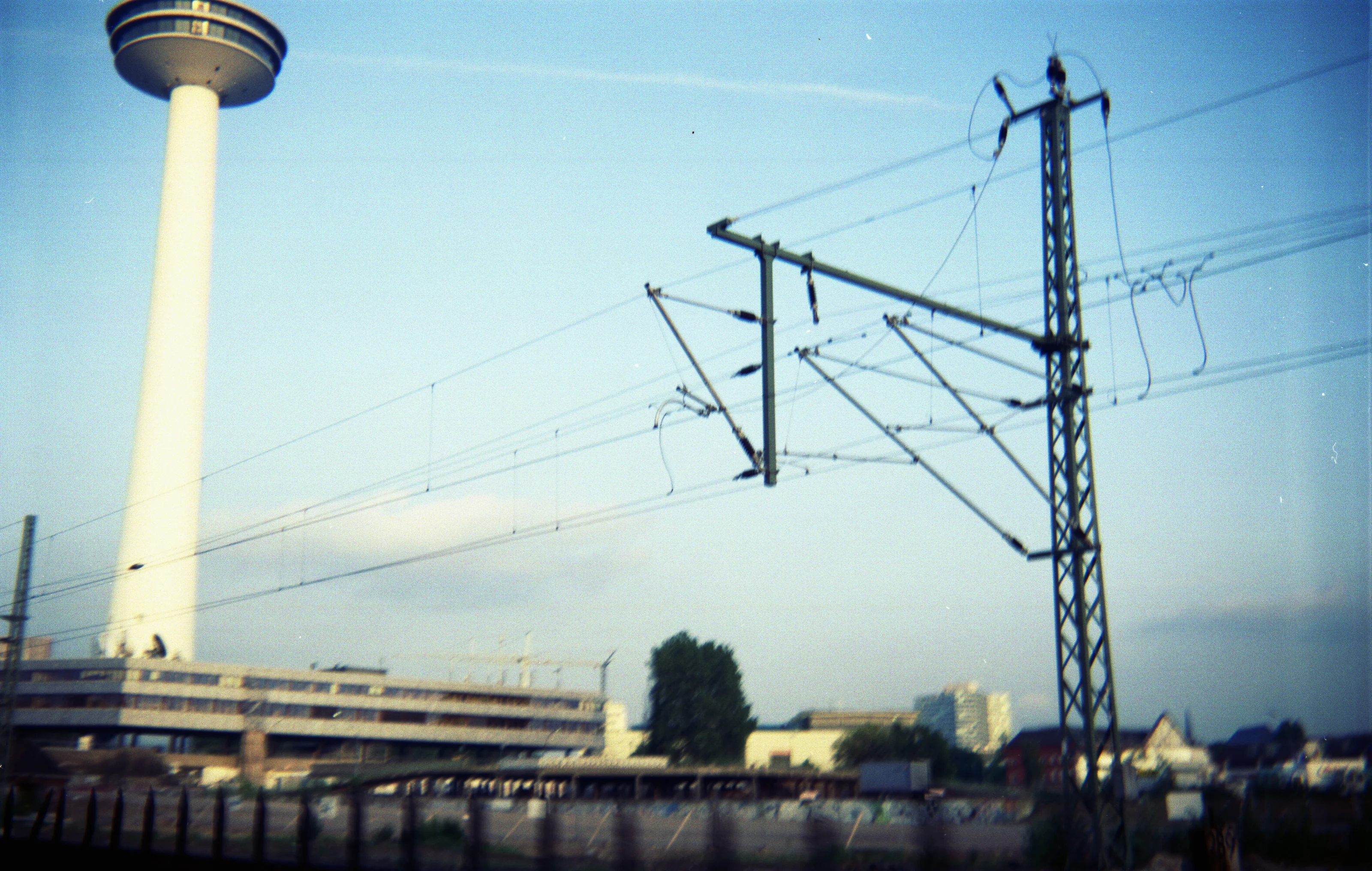 A tall observation tower next to railway power lines against a blue sky.