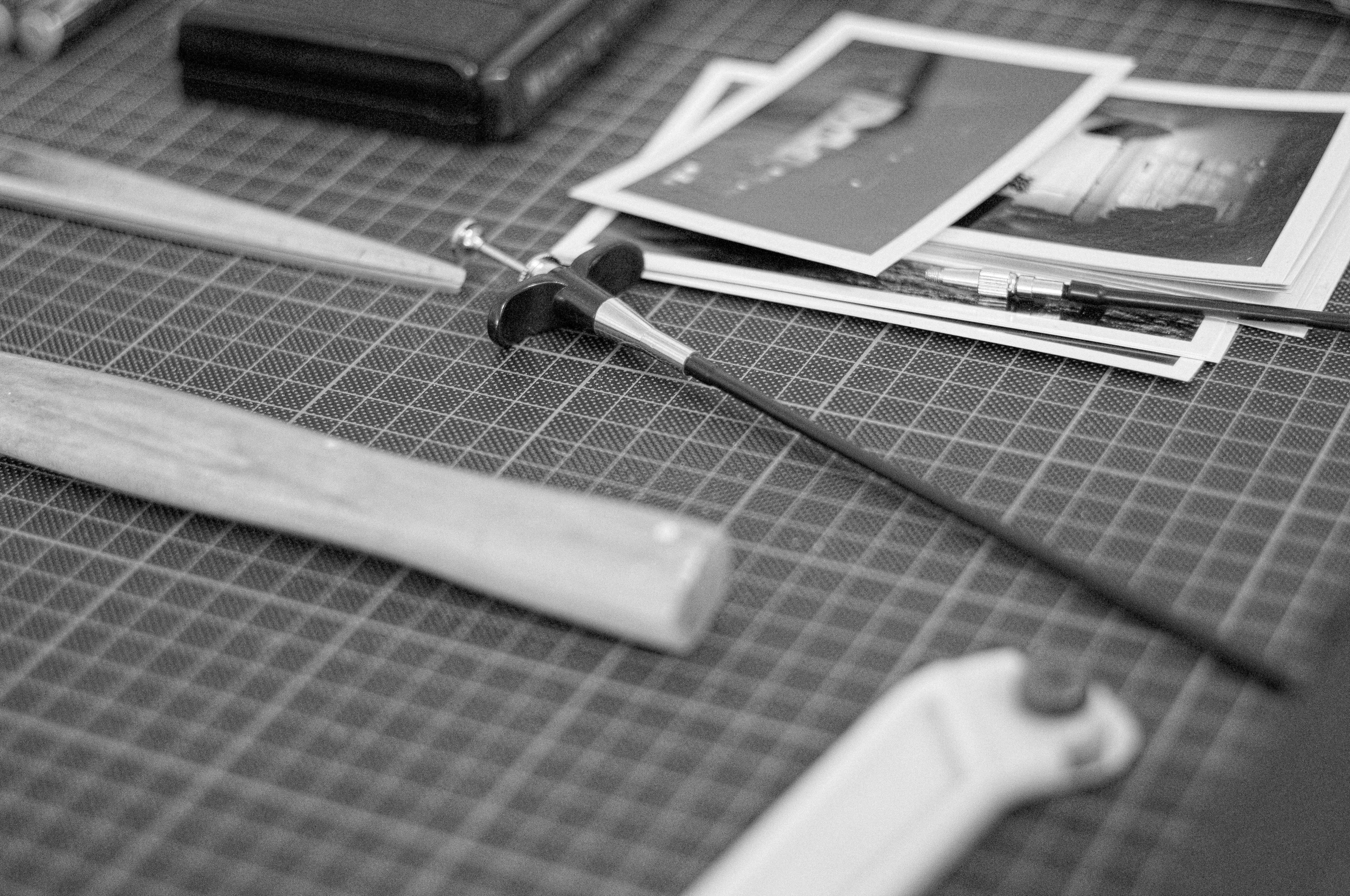 A cutting tool and printed photos on a gridded cutting mat.