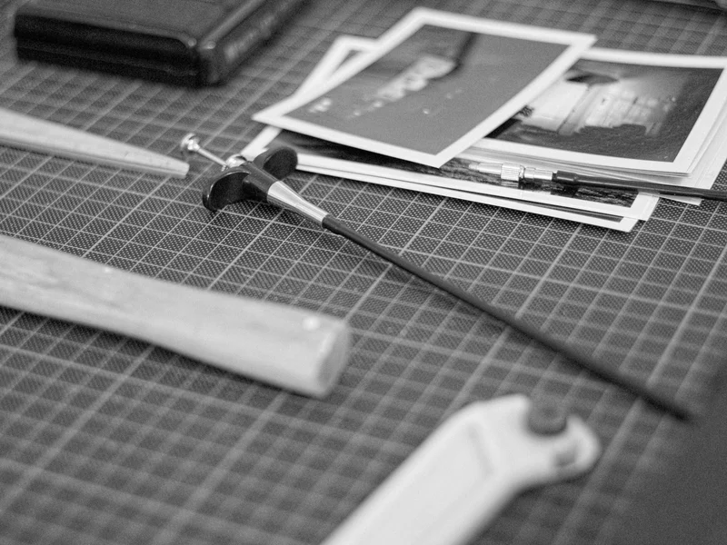 A cutting tool and printed photos on a gridded cutting mat.