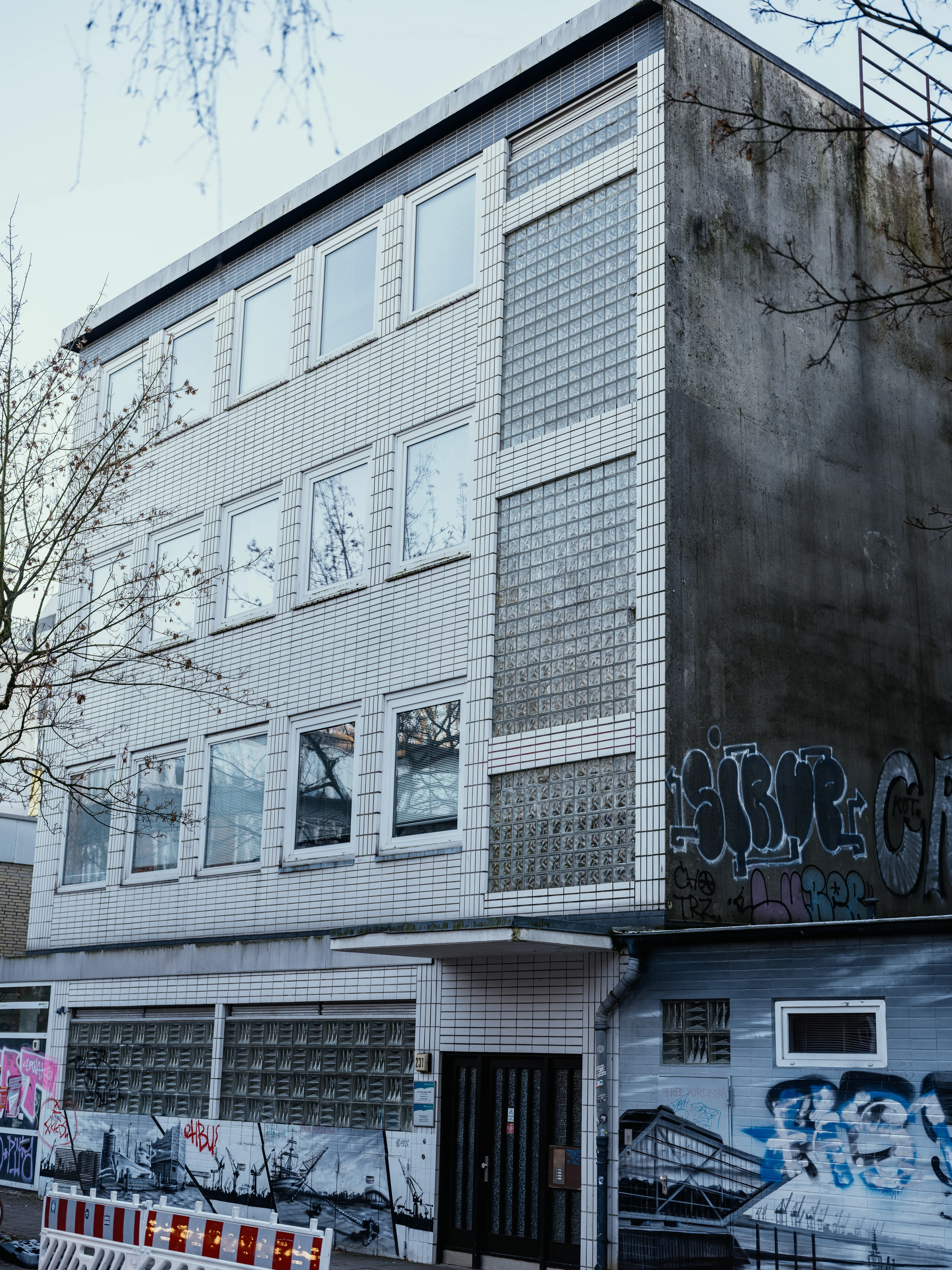 A multi-story building with tiled facade and graffiti on the lower level.