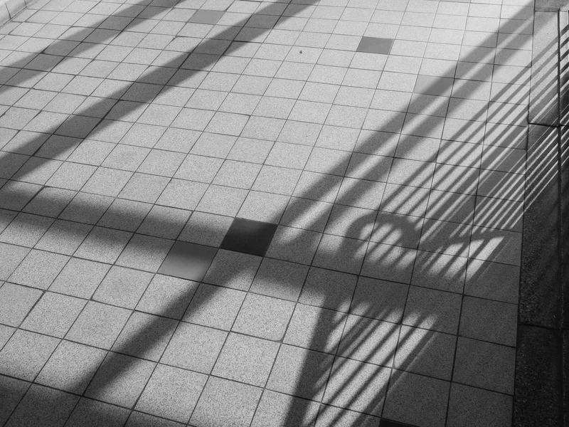 Shadows of a railing cast on a tiled floor.