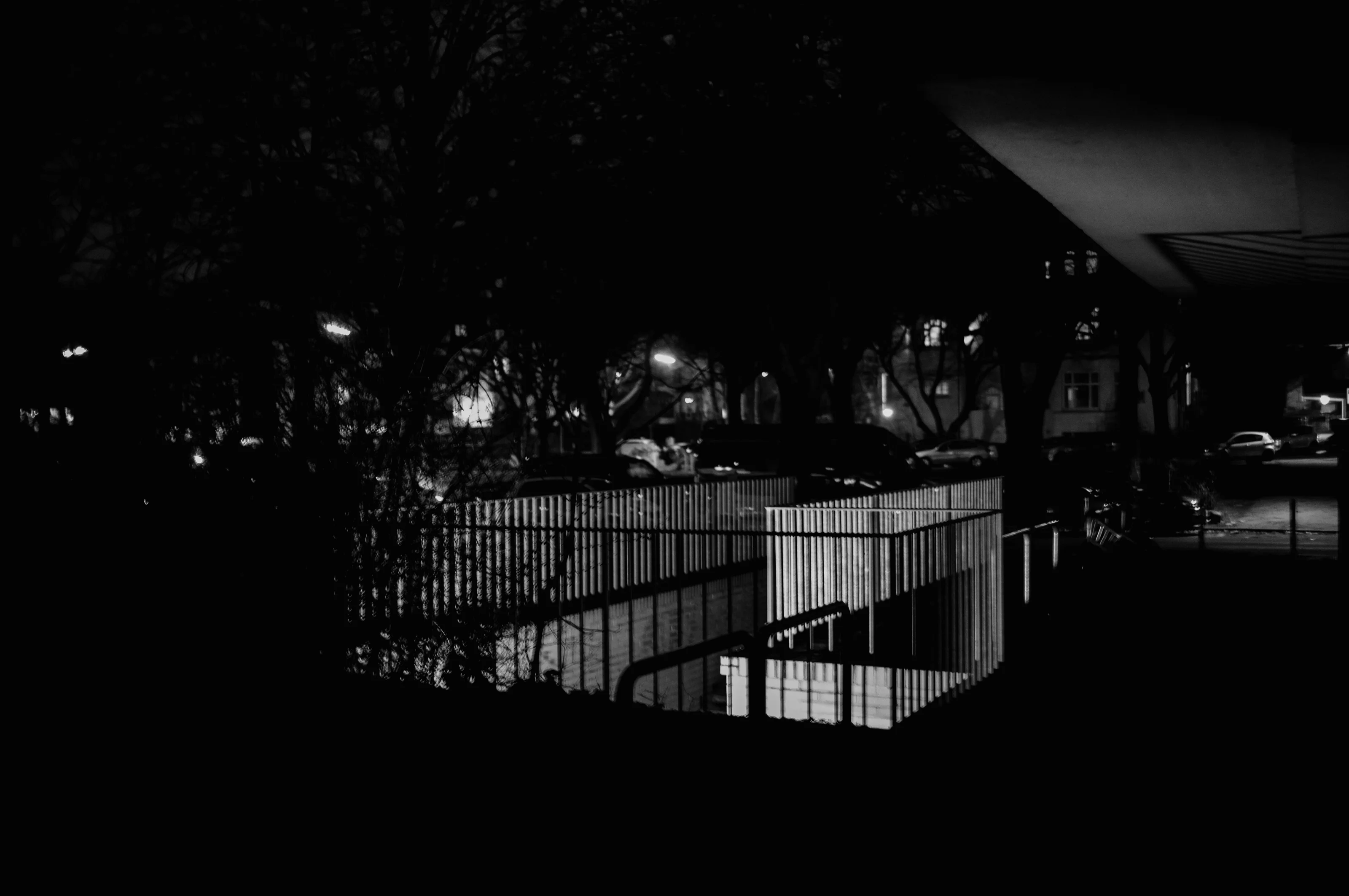 A nighttime scene showing illuminated railings and shadows in an urban environment.