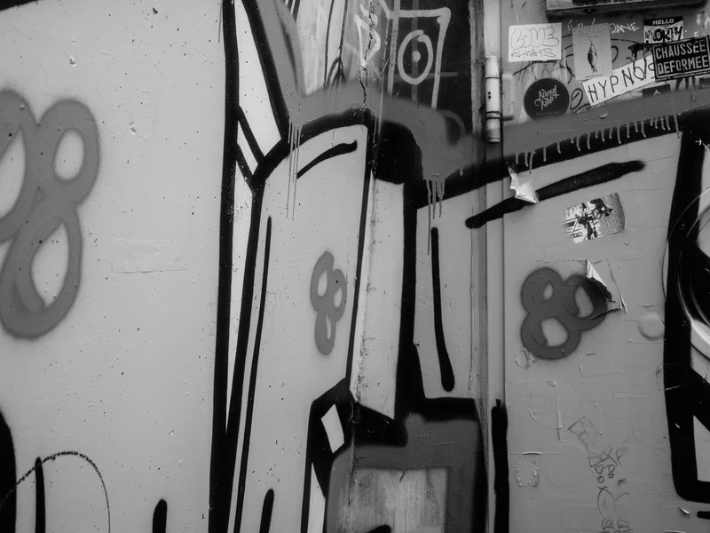 Black and white graffiti on a corner wall with abstract shapes and stickers.