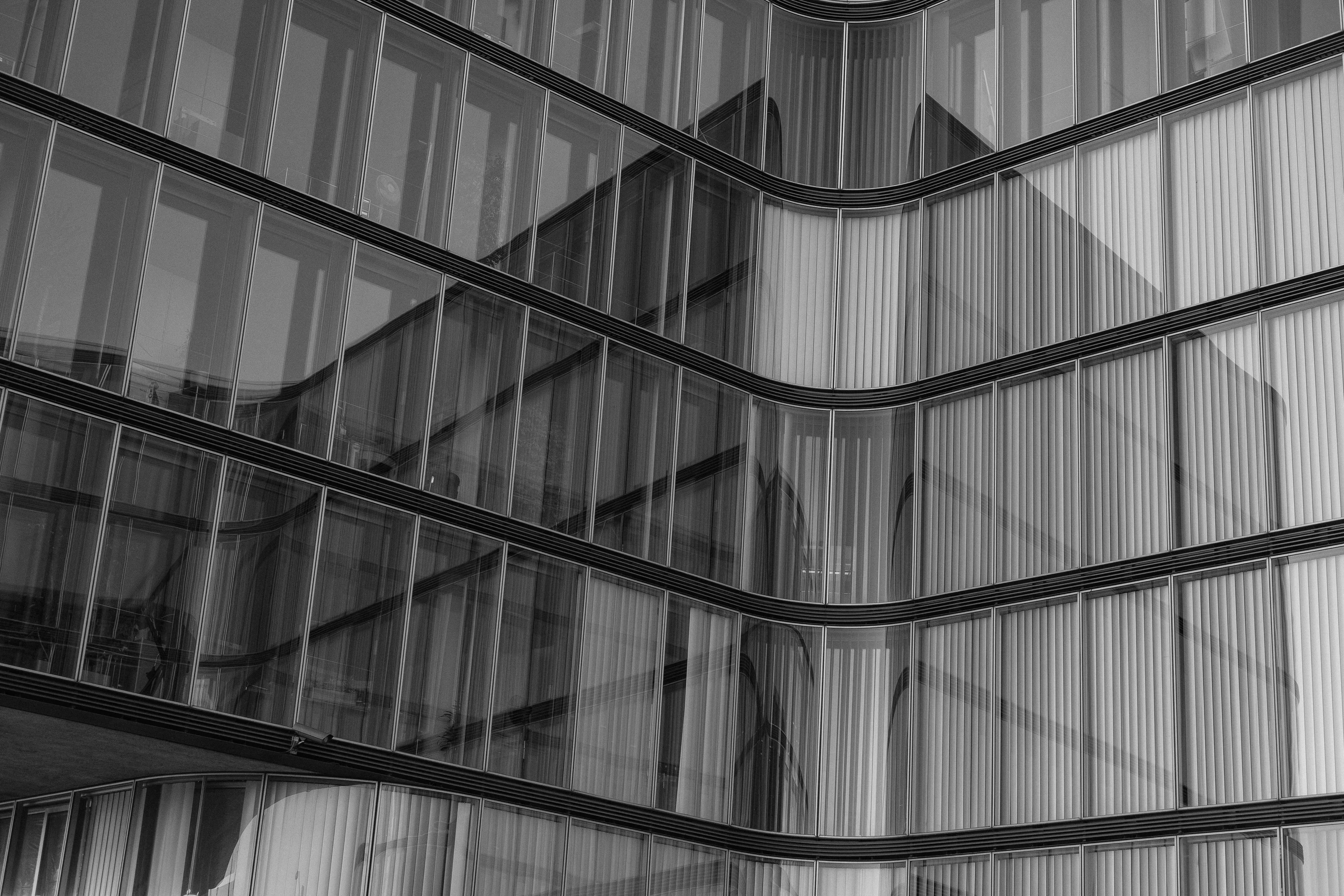 Black and white architectural shot of a modern glass building with reflections.