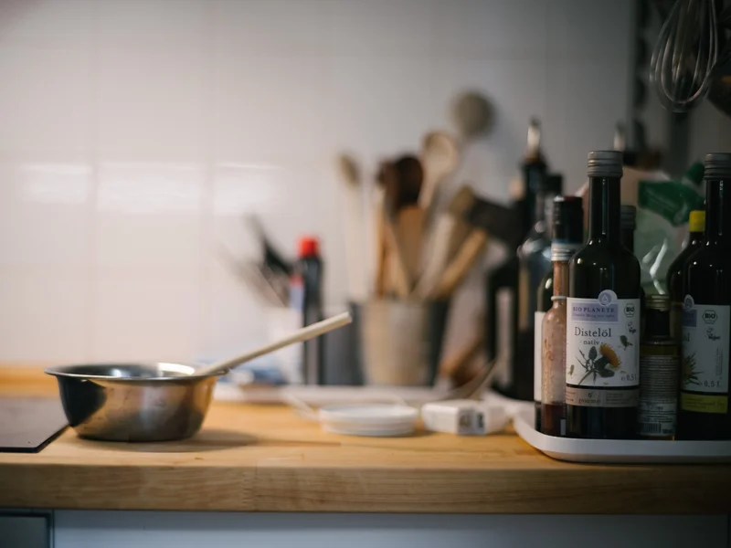 A kitchen countertop with cooking utensils and bottles of oil.