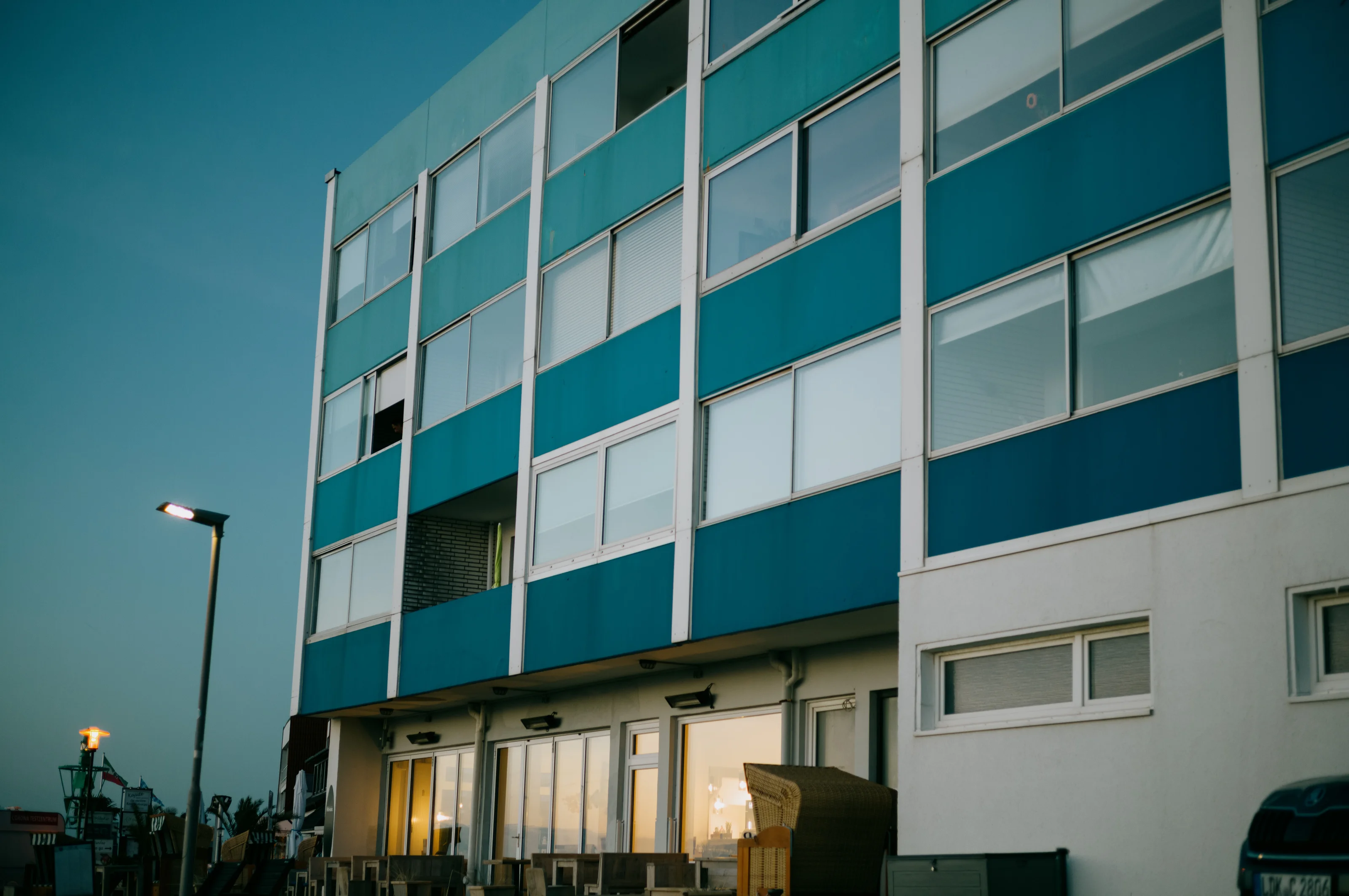 Modern apartment building with blue and white panels at dusk.