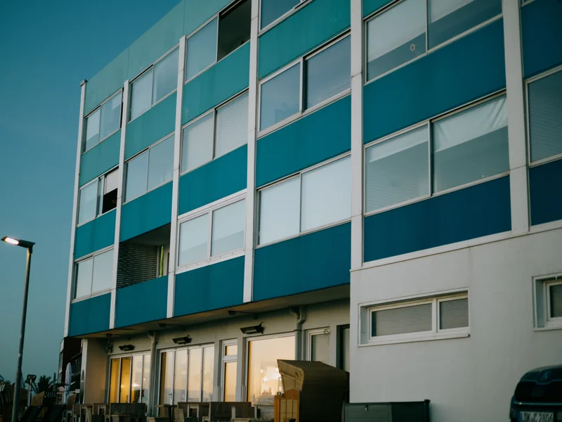 Modern apartment building with blue and white panels at dusk.