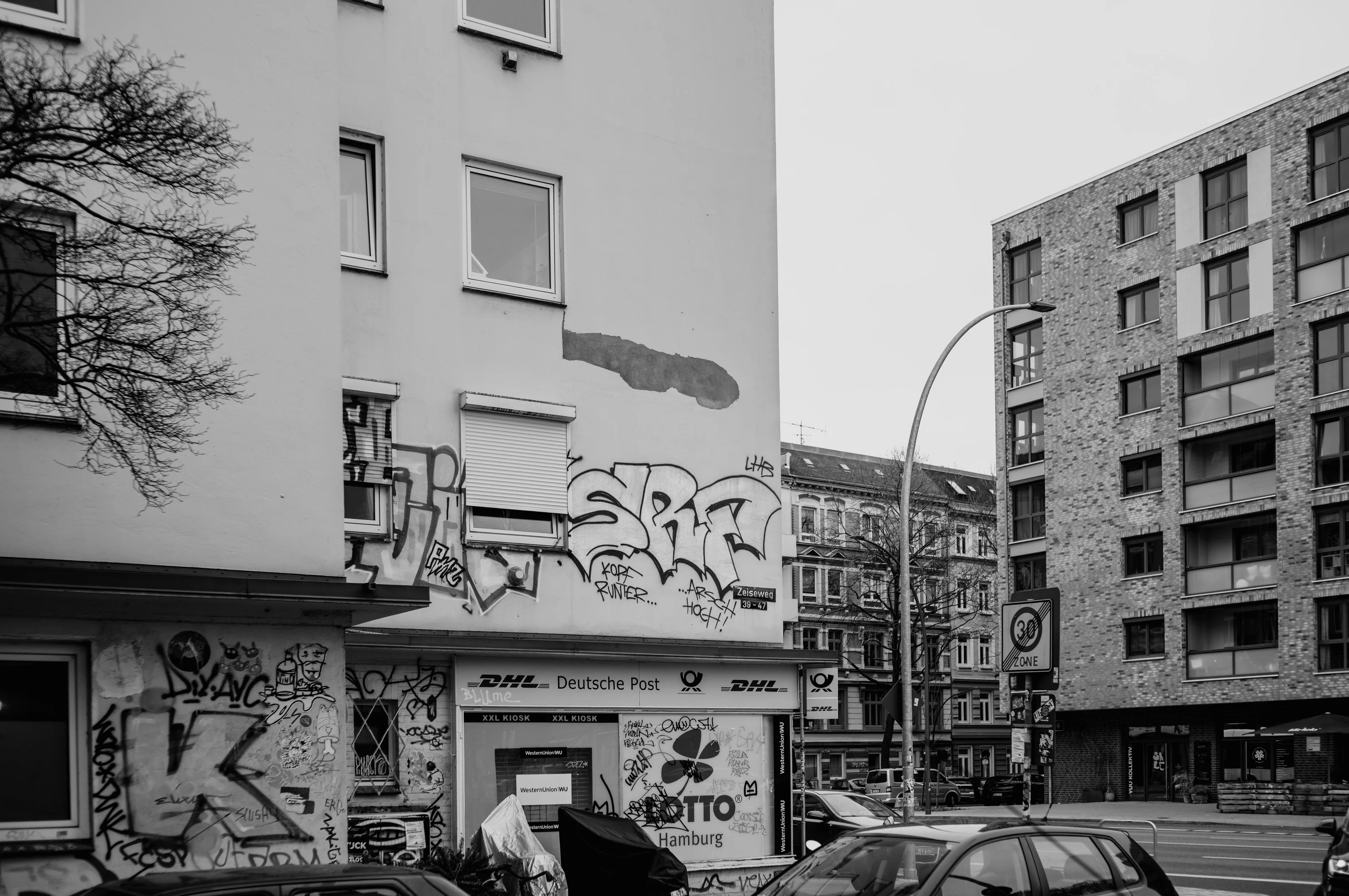 Street view with graffiti-covered building facade and modern apartments.