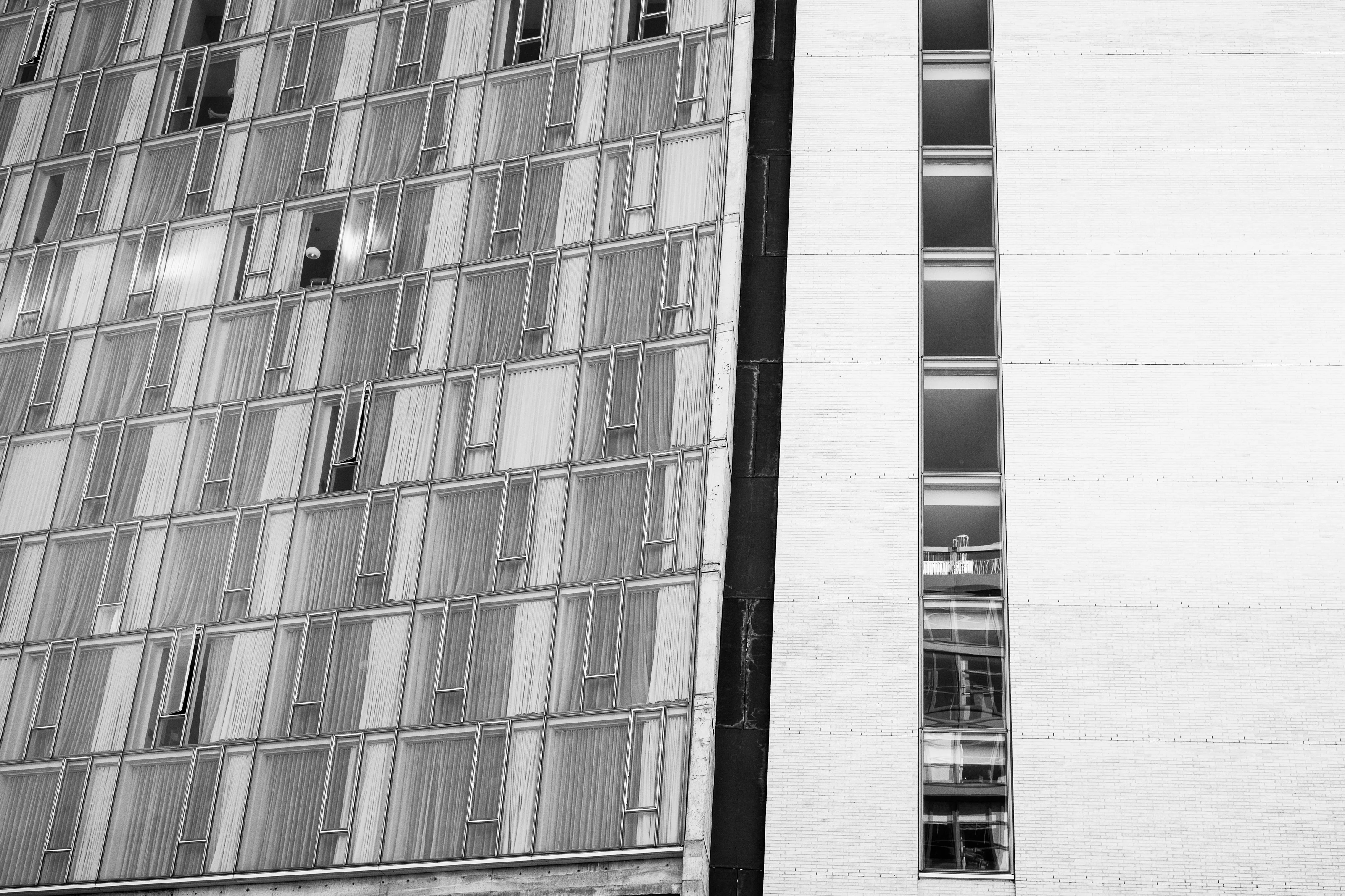 Black and white photo of two adjacent building facades with vertical windows.