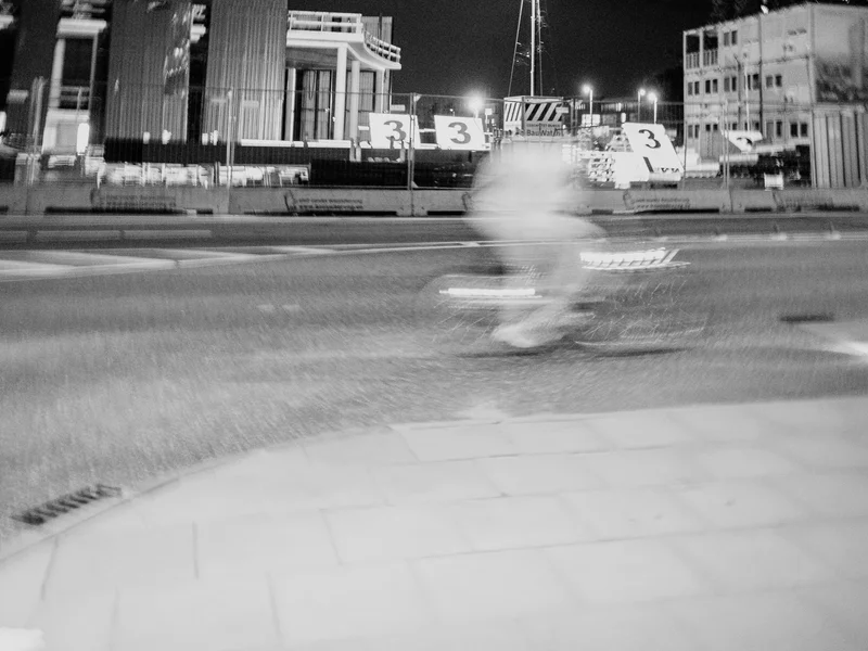 Blurred cyclist passing by a construction site at night.